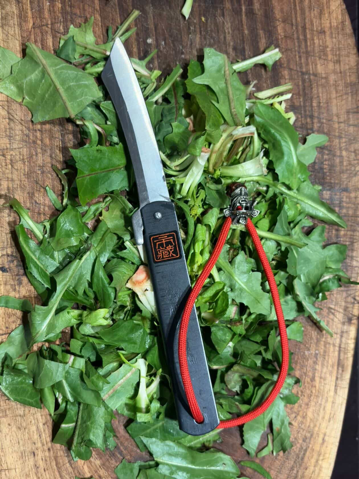 Ichizo Honpo Higonokami knife open on fresh herbs on wooden cutting board