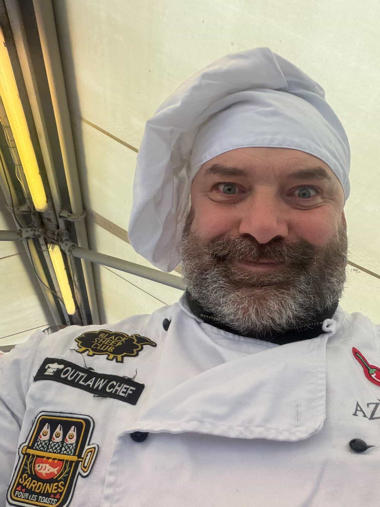 Outlaw Chef Damjan Bistričić — portrait in chef's hat with OUTLAW CHEF patches