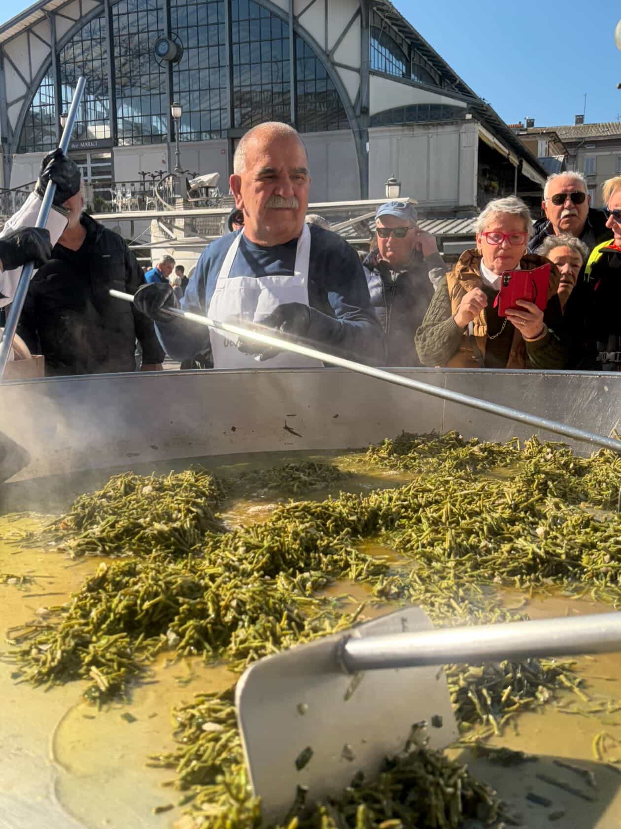 Chef working the giant frittata pan with a long-handled spatula, crowd watching