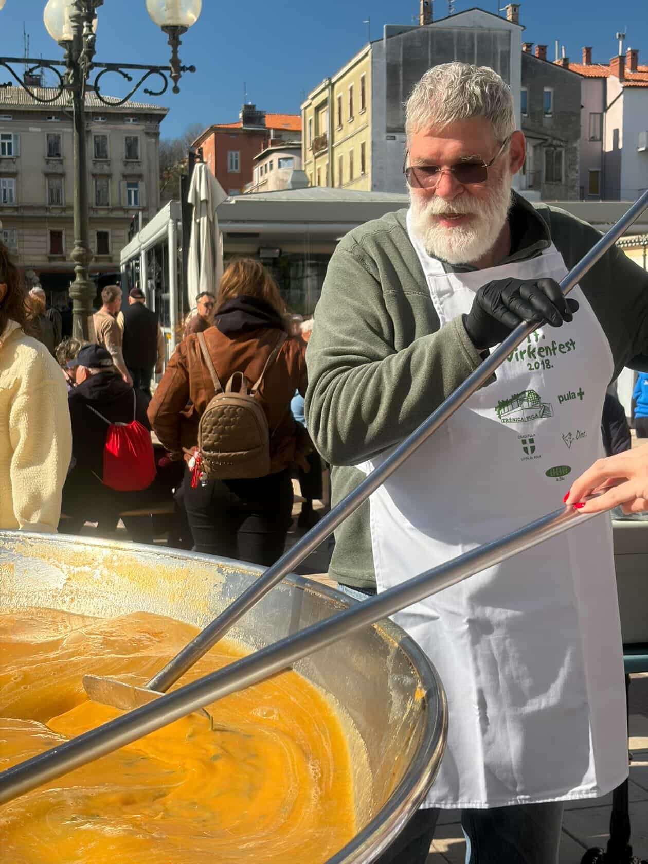 Silver-haired chef at the giant pan