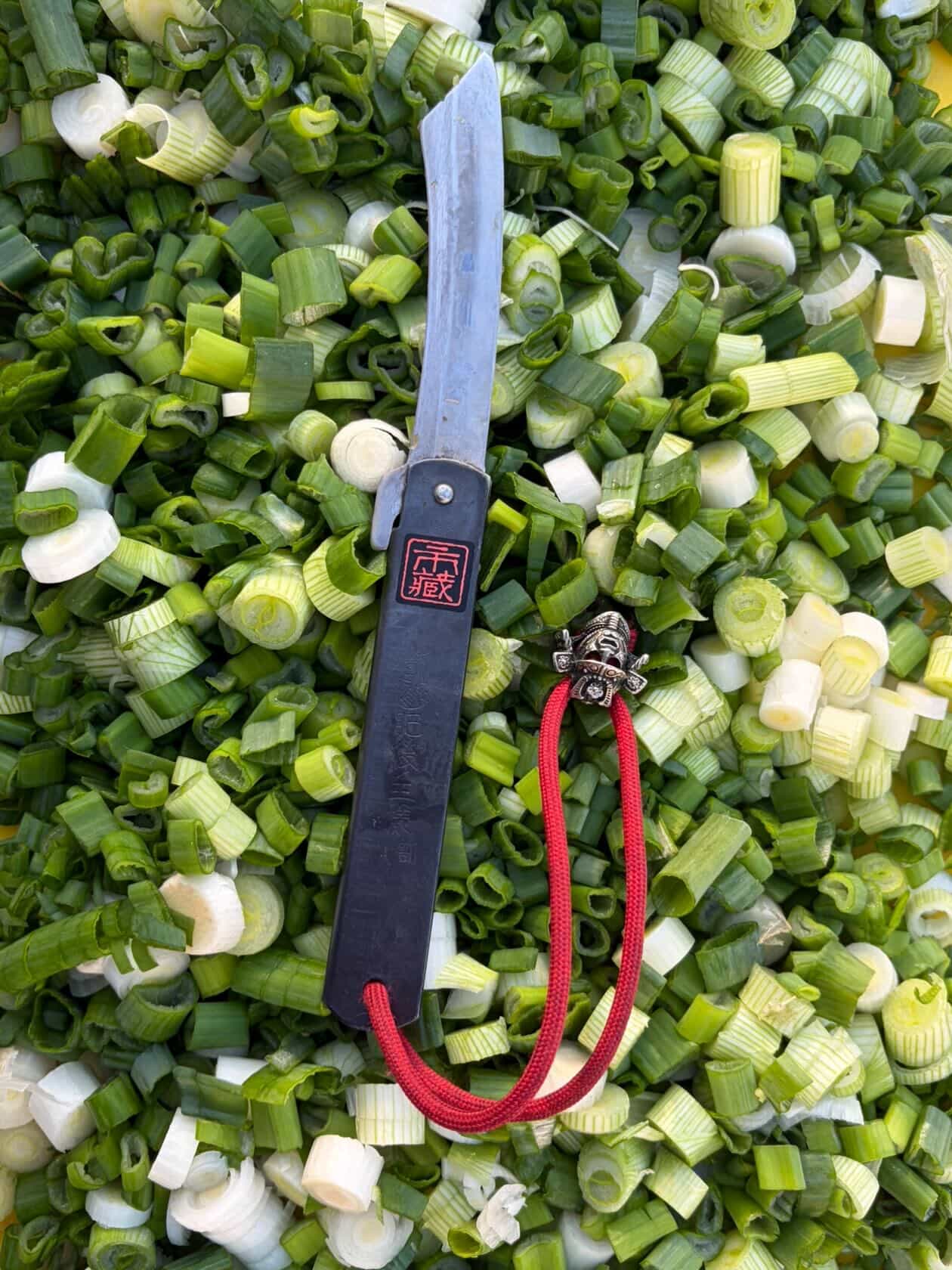 Ichizo Honpo Higonokami lying across a sea of chopped spring onions