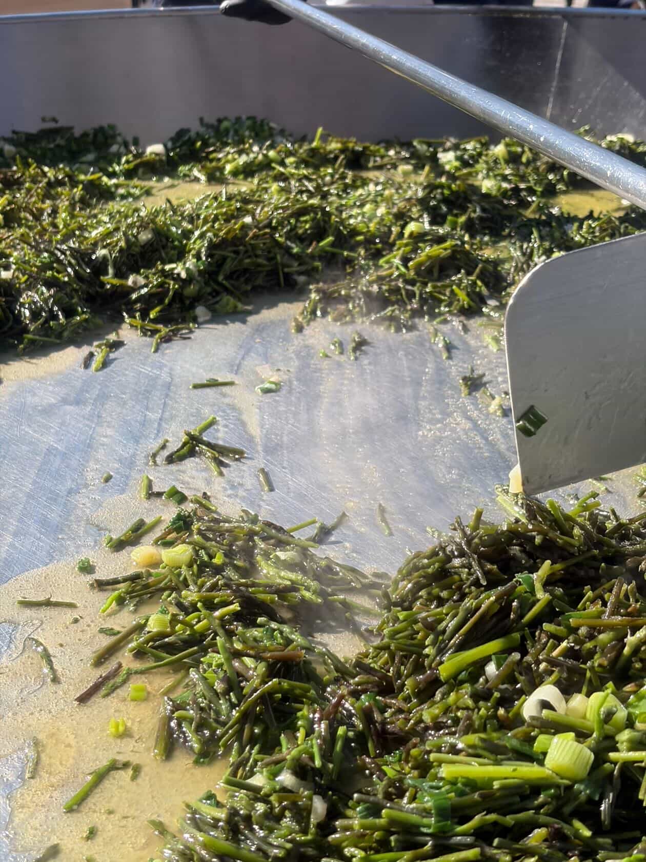 Wild asparagus and spring onions cooking on a giant steel pan at the spring festival