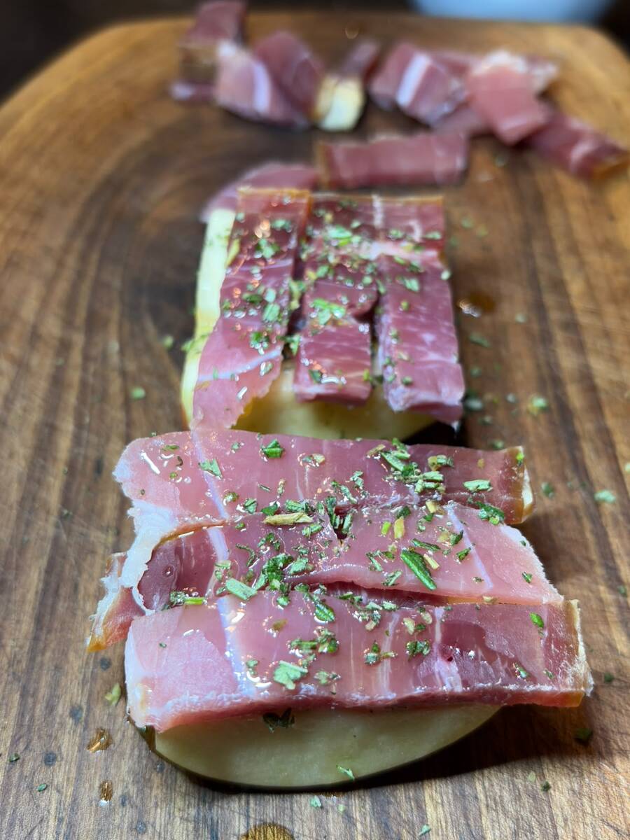 Strips of prosciutto laid on a cut apple, sprinkled with chopped rosemary