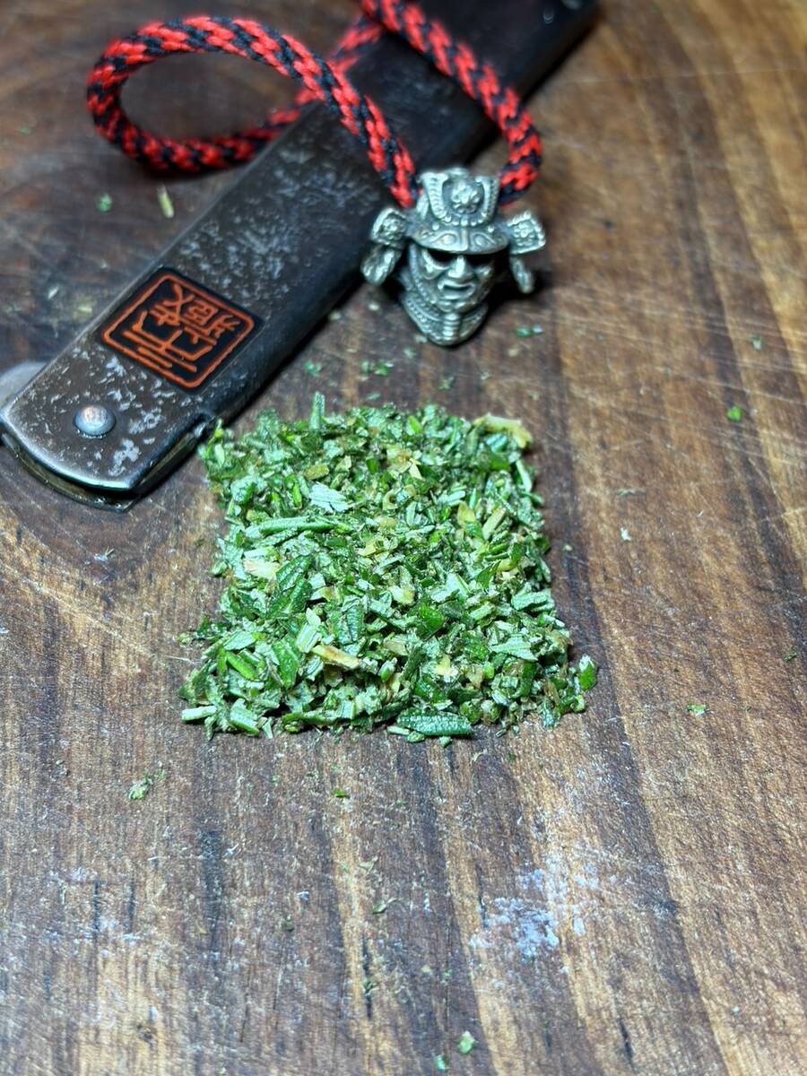 Finely chopped rosemary beside a Higonokami bearing the Ichizo stamp
